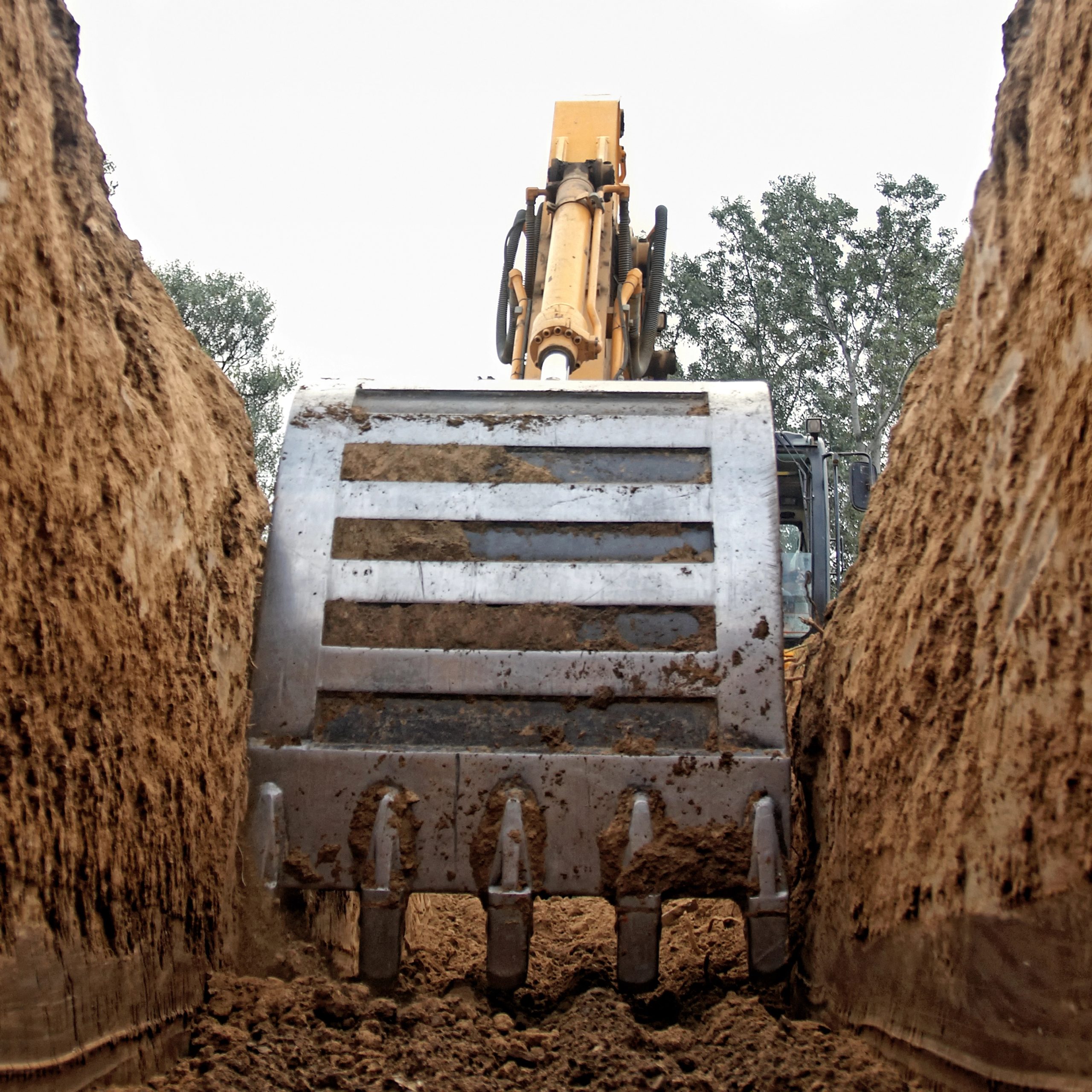 Excavator bucket working between banks of soil